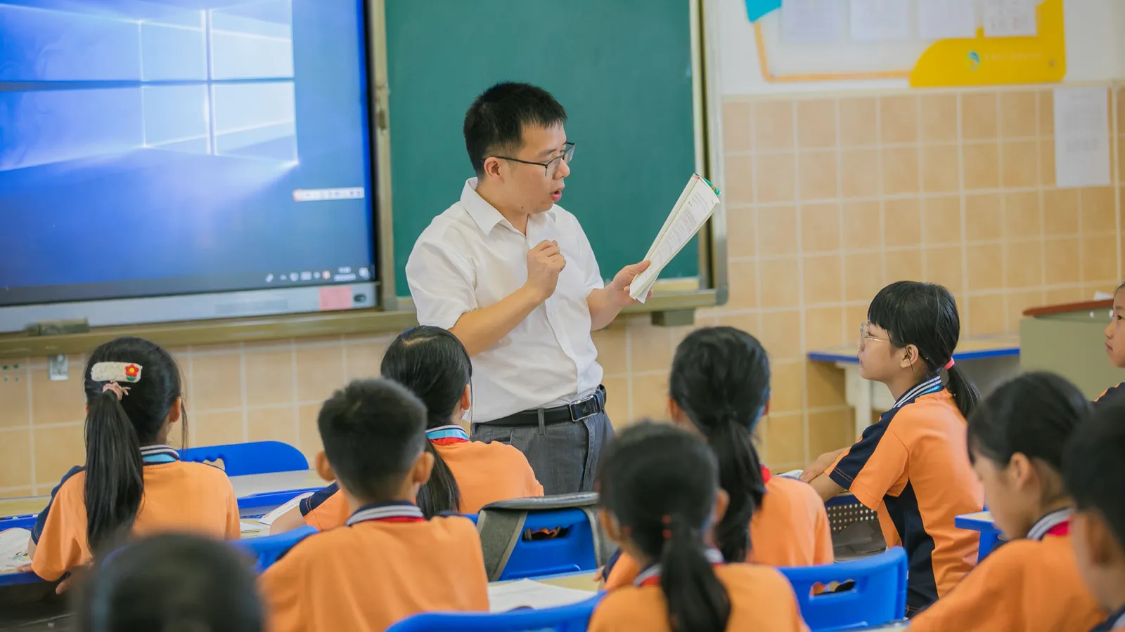 中師在教室前拿著講義授課，穿制服的學生坐在課桌前聽講