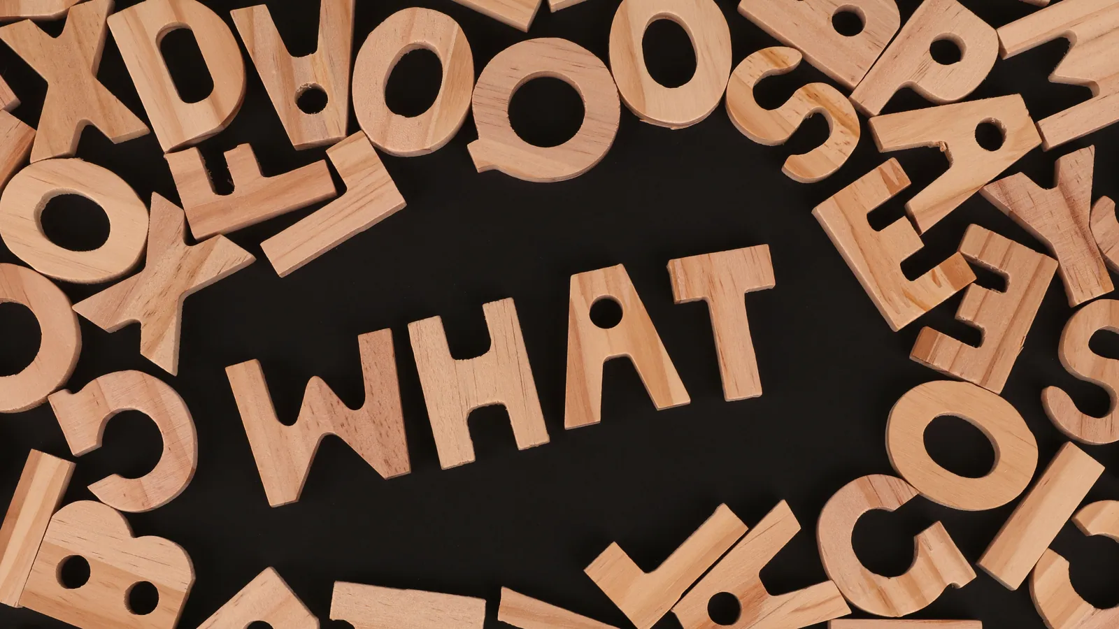 木製英文字母排出 WHAT 一字，象徵拆解雙語教育的常見疑問